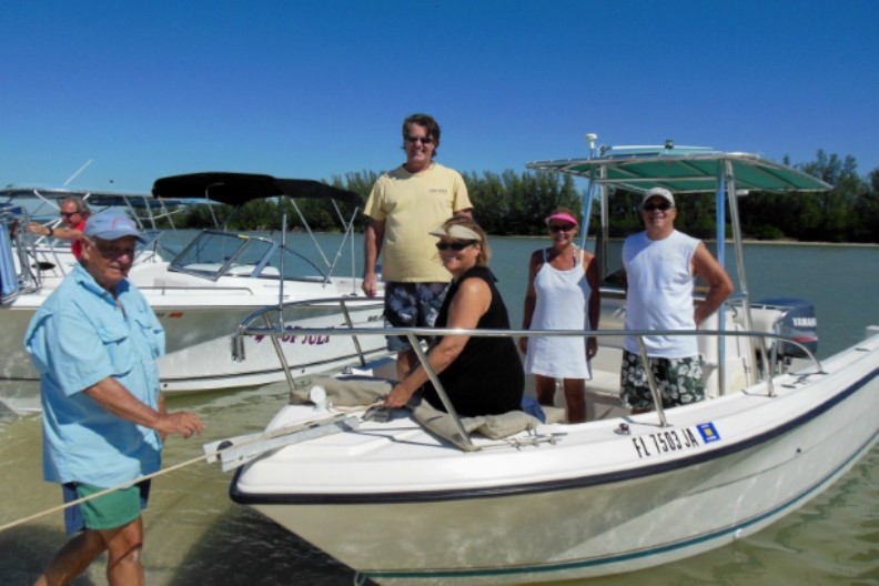 Photo, men and women in and around boats pulled up to a SW Florida beach